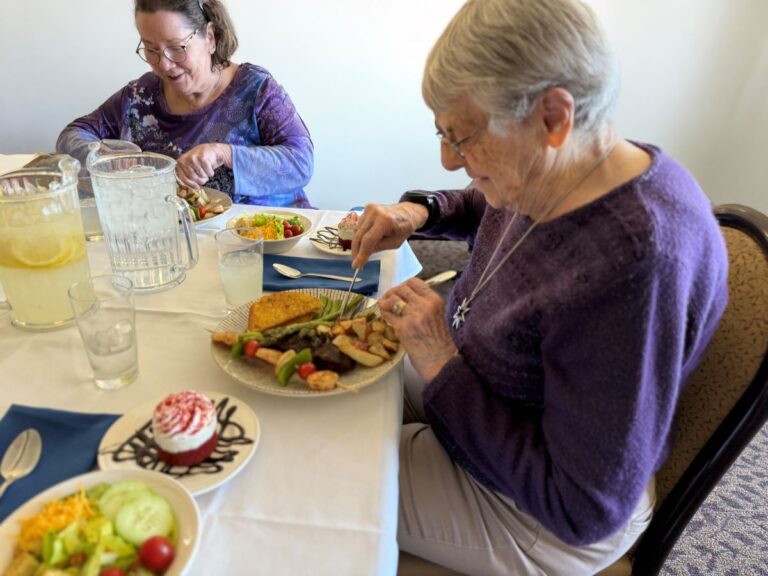 Senior females seated at a dinner table with food on their plates
