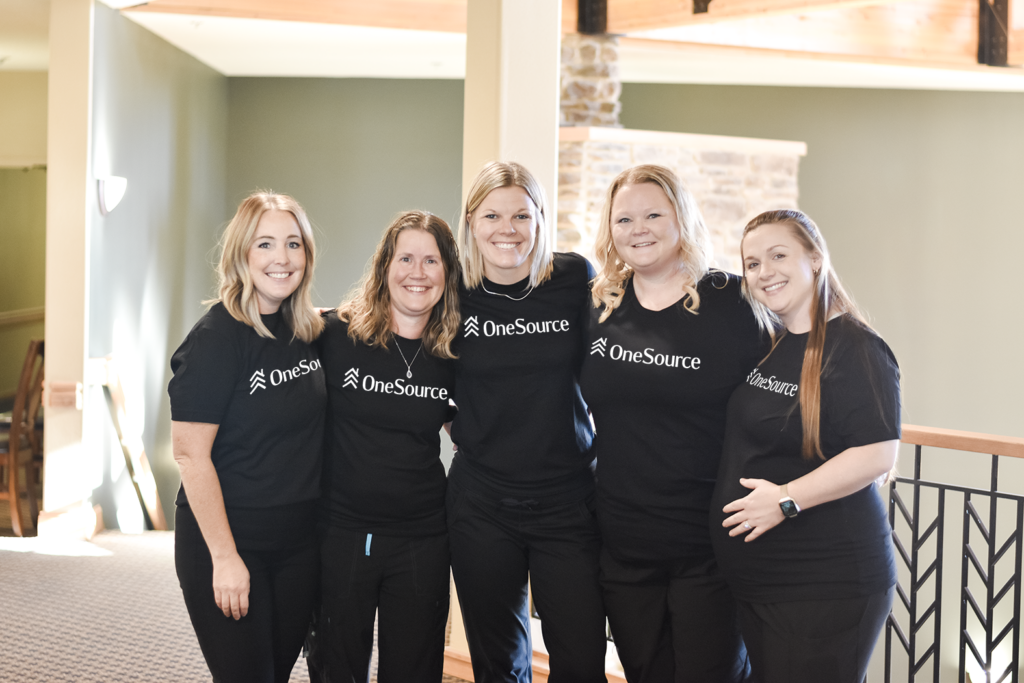 Five female OneSource team members all wearing matching OneSource T-Shirts